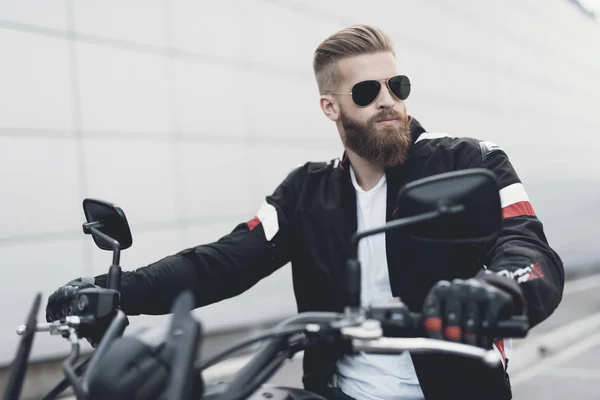 Молодий хлопець з бородою сидить на своєму електричному мотоциклі . — стокове фото