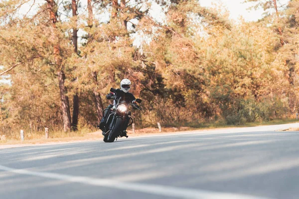 Un jeune homme avec un casque roule sur une route forestière sur une moto électrique . — Photo