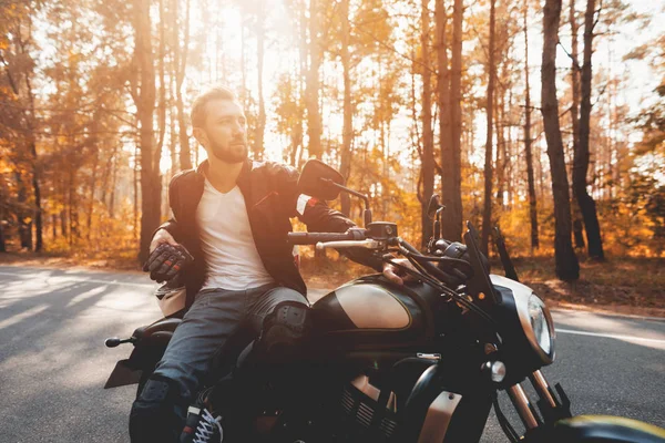 Um jovem com barba está sentado em sua moto elétrica . — Fotografia de Stock