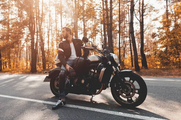 Mladý muž s plnovousem a sedí na jeho elektrický motocykl. — Stock fotografie