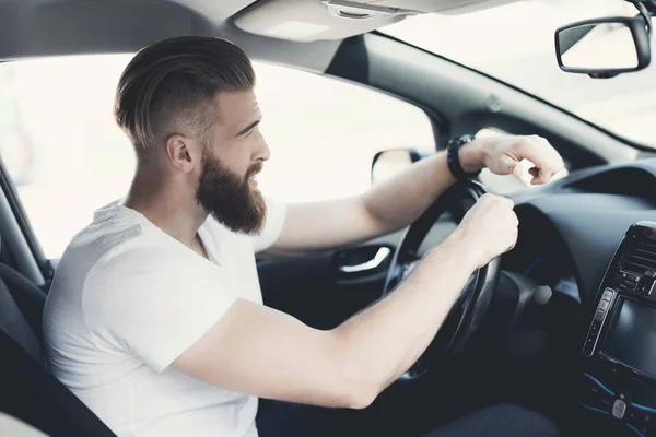 Un giovane con la barba siede al volante di un veicolo elettrico . — Foto Stock