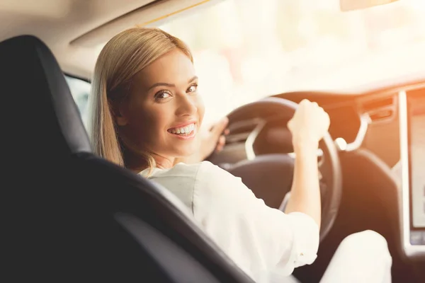 Uma jovem senta-se ao volante de um carro elétrico moderno . — Fotografia de Stock