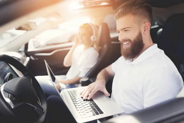 A young man with a beard sits at the wheel of an electric vehicle.