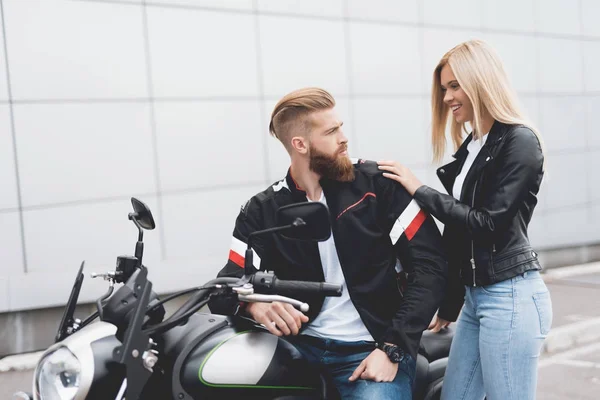 Young guy and girl sitting on a modern electric motorcycle.