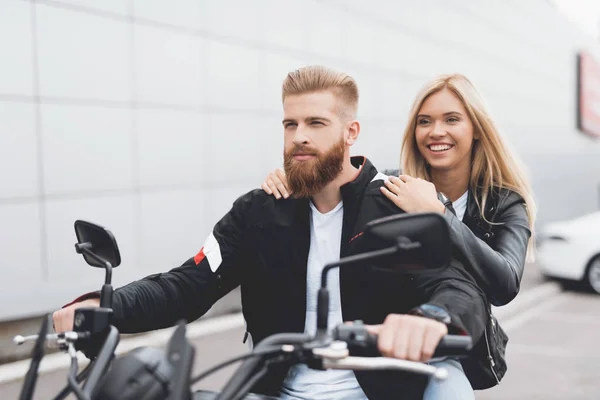 Joven chico y chica sentado en una motocicleta eléctrica moderna . — Foto de Stock