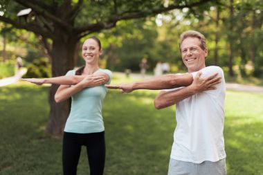 Erkek ve kadın parkta egzersizleri yapıyor. Onlar ısınmak
