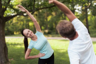 Erkek ve kadın parkta egzersizleri yapıyor. Onlar ısınmak.