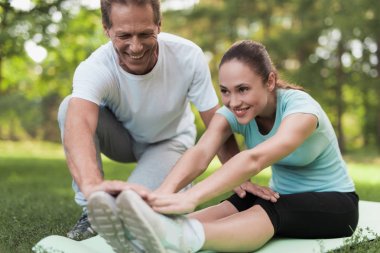 Bir kadın için yoga ve bir ısınma yapıyor bir halı üzerinde parkta oturuyor.