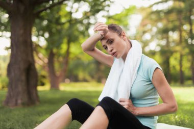 Bir kadın için yoga bir halı üzerinde oturan ve bir egzersiz yaptıktan sonra dinlenme. Onun arkasında yoga için mavi bir toptur.