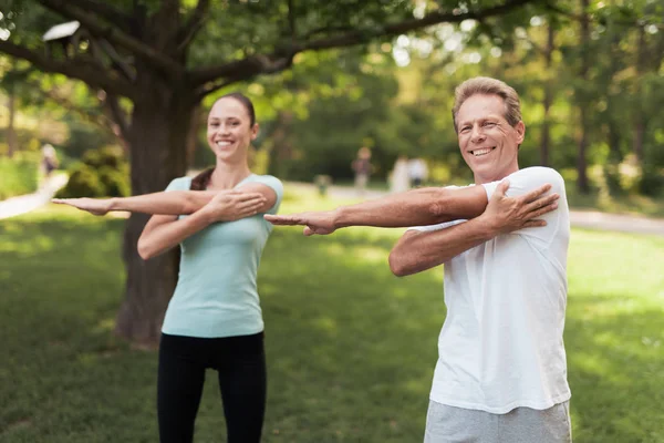Erkek ve kadın parkta egzersizleri yapıyor. Onlar ısınmak