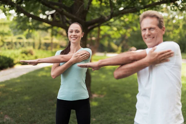 Homem e mulher fazendo exercícios no parque. Eles aquecem. — Fotografia de Stock