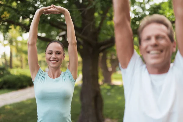 Paar macht Übungen im Park. sie strecken die Hände aus — Stockfoto