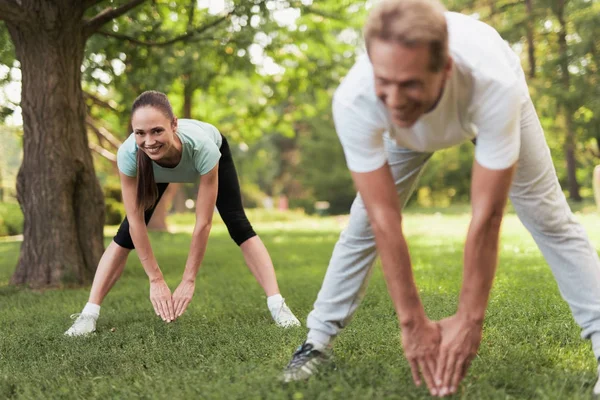 Couple doing physical exercises in nature. They make the slopes together.