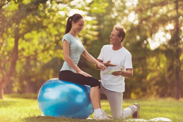 Mężczyzna i kobieta robi ćwiczenia jogi w parku. Człowiek jest szkolenie Kobieta — Zdjęcie stockowe