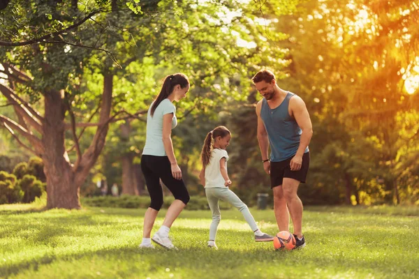 Aile parkta futbol oynuyor. Kırmızı Top oynuyorlar — Stok fotoğraf