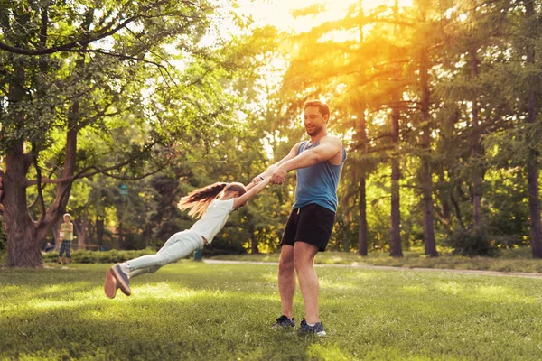 Padre e hija están jugando en el parque. Un hombre está convirtiendo a una chica. Se están divirtiendo. — Foto de Stock