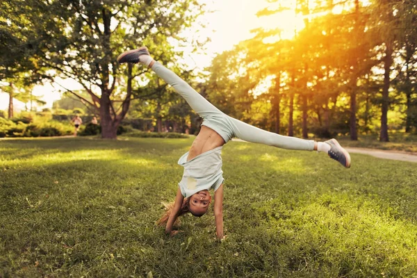 Das Mädchen liegt sich im Park in den Armen. Sie hat Spaß — Stockfoto