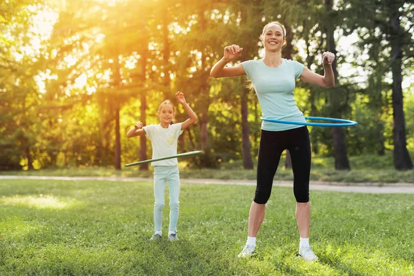 Una ragazza con sua madre che pratica con cerchi ginnici nel parco — Foto Stock