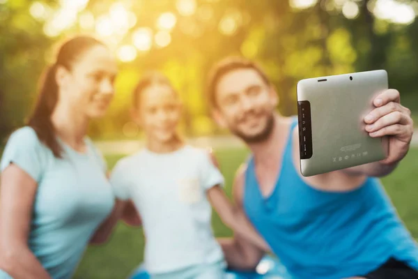 Ένας άνδρας κάνει μια selfie στο tablet του με τη γυναίκα και την κόρη. Είναι στο πάρκο. — Φωτογραφία Αρχείου