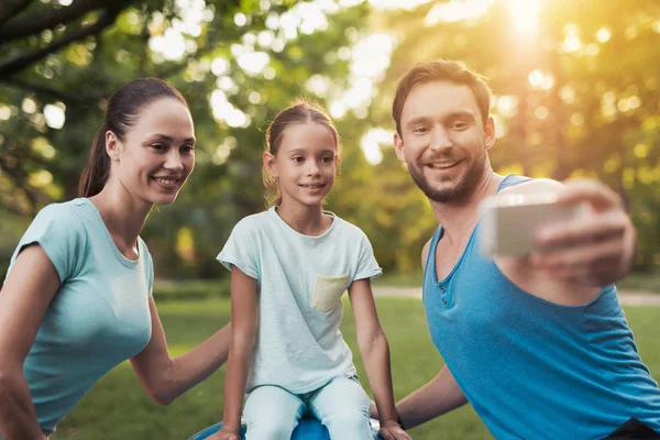 A família descansa no parque depois de praticar esportes. Um homem faz selfie com sua família — Fotografia de Stock