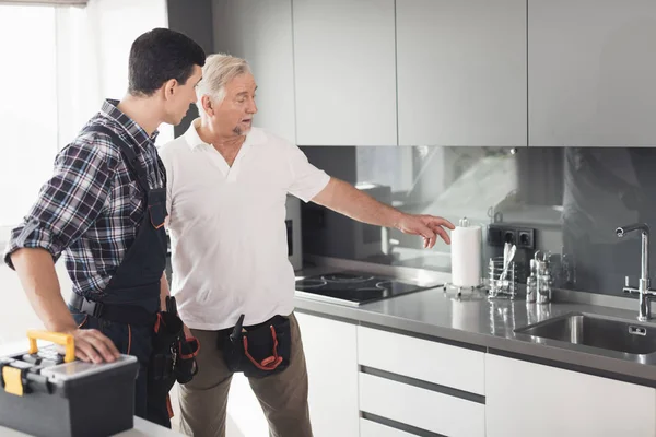 Два чоловіки сантехніки стоять на кухні і оглядають майбутні майданчики для ремонту . — стокове фото