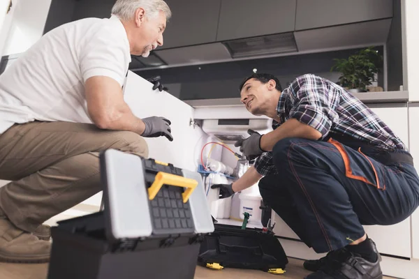 两个水管工准备修理净水器。他们选择合适的工具来修理设备. — 图库照片