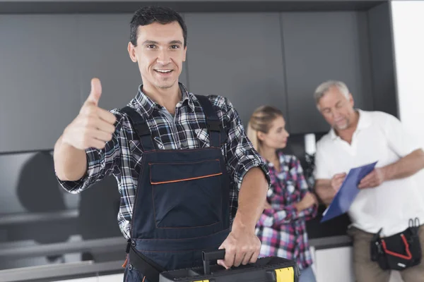 The plumber is posing in the kitchen. He shows his thumb up and smiles. — Stock Photo, Image