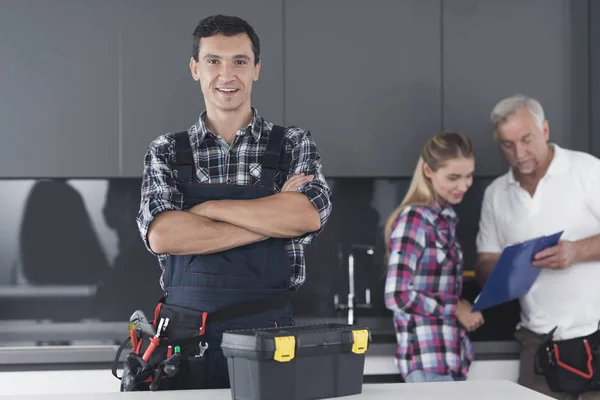 L'idraulico sta posando in cucina. Sta con le braccia incrociate e sorride . — Foto Stock