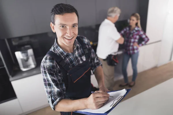 El fontanero posa en la cocina. Rellena el formulario y sonríe . — Foto de Stock