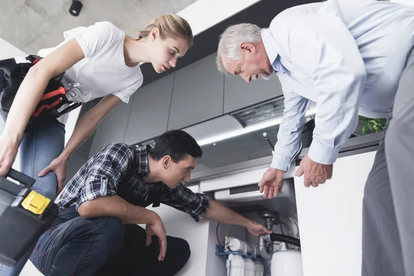 A man and a woman of sanitary engineering came to a call to an elderly man. He talks about the problem with the pipes. — Stock Photo, Image