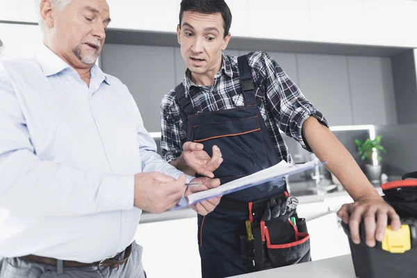 El fontanero se comunica con el cliente y le muestra la cuenta del trabajo realizado . —  Fotos de Stock