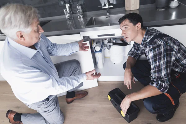 Een loodgieter man spreekt met een klant die ontevreden met het werk is. — Stockfoto