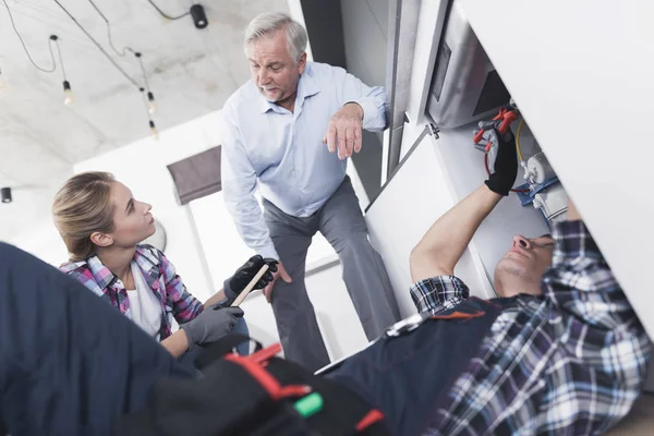 The old man controls the work of a pair of fittings, which he called for repairs. — Stock Photo, Image