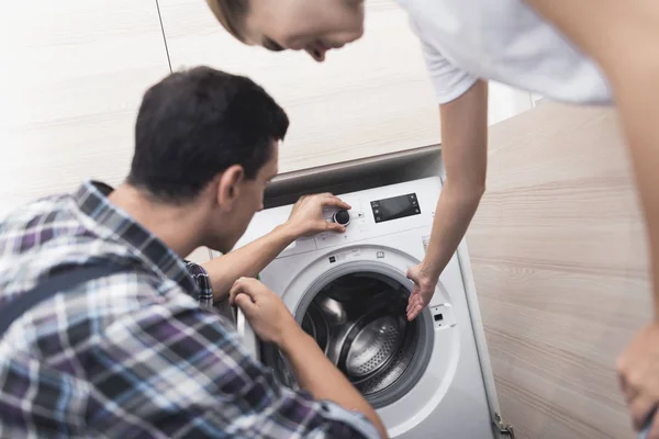 Rief die Frau den Reparateur der Waschmaschine an. Zusammen mit dem Meister untersucht sie die Waschmaschine. — Stockfoto