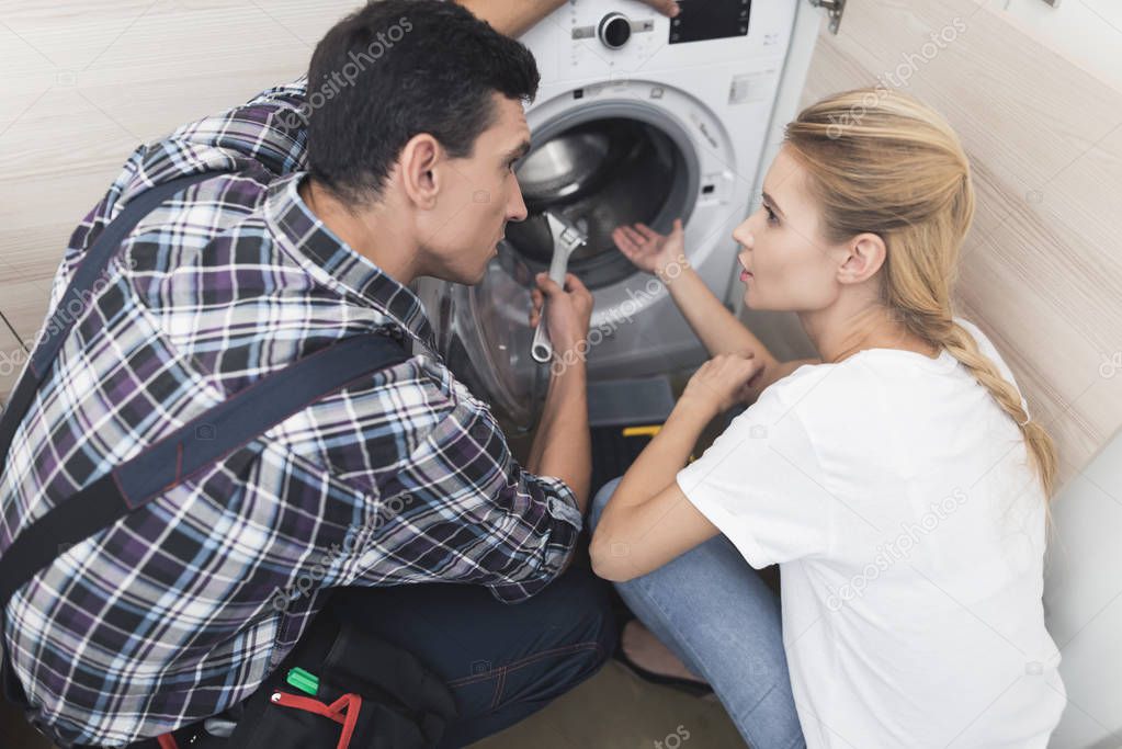 The woman called the repairman of the washing machine. She, along with the master, examines the washing machine.