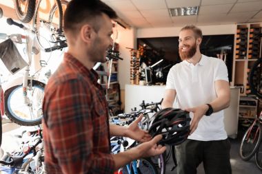 Adam satıcının alıcı Bisiklet kask rides gösterir.