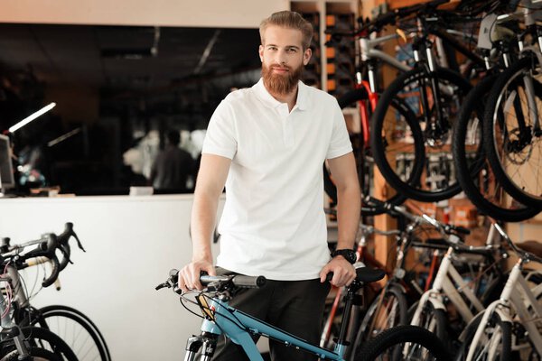 A salesman in a bicycle shop poses near a bicycle.