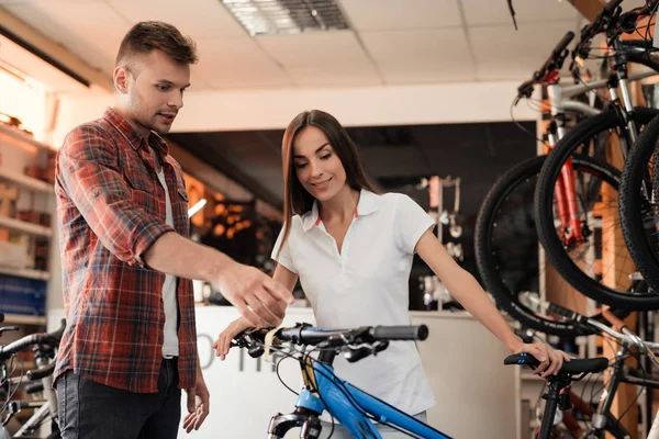 Beraterin zeigt dem Käufer in einem Fahrradgeschäft. — Stockfoto