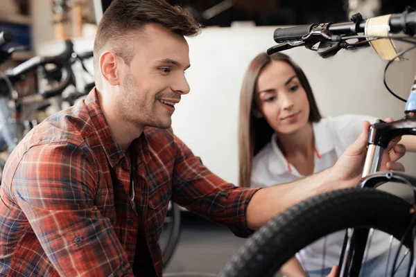 Una chica consultora muestra al comprador en una tienda de bicicletas . — Foto de Stock