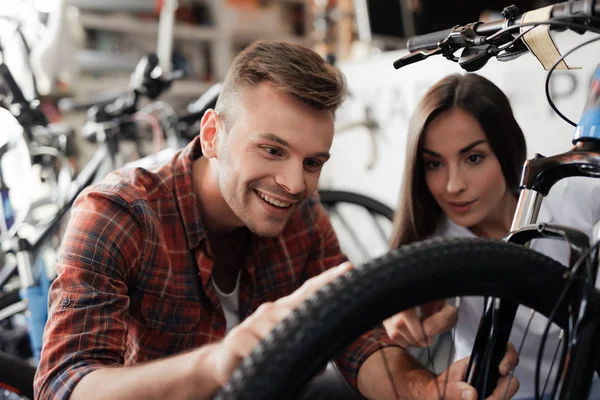 A girl consultant shows the buyer in a bicycle store. — Stock Photo, Image