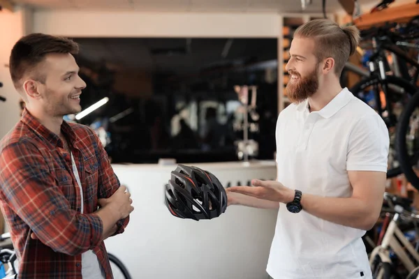 Der Verkäufer zeigt dem Käufer einen Fahrradhelm. — Stockfoto