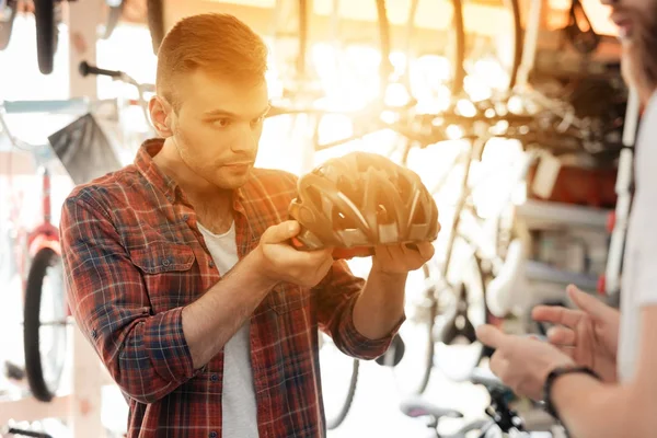 Der Verkäufer zeigt dem Käufer einen Fahrradhelm. — Stockfoto