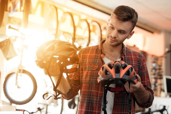 Молодой человек внимательно смотрит на шлемы для езды на велосипеде . — стоковое фото