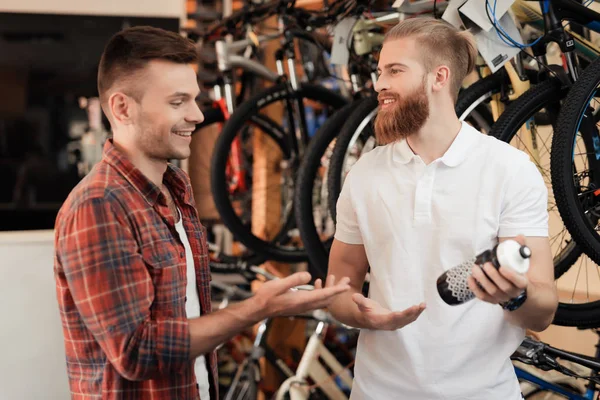 Verkäufer im Fahrradgeschäft hilft jungen Käufern bei der Auswahl einer Wasserflasche für Fahrradtouren. — Stockfoto