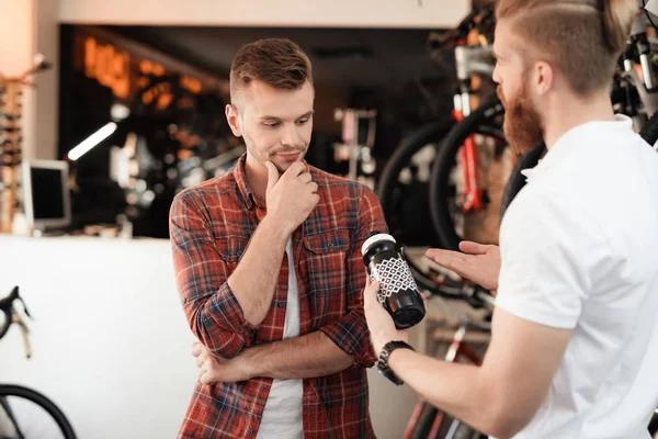 A salesperson at a bicycle store helps a young buyer choose a water bottle for bike rides. — Stock Photo, Image