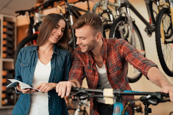 Um jovem casal veio à loja de bicicletas para escolher uma nova bicicleta . — Fotografia de Stock