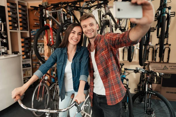 Ein junger Mann und ein Mädchen machen ein Selfie in einem Fahrradgeschäft. — Stockfoto