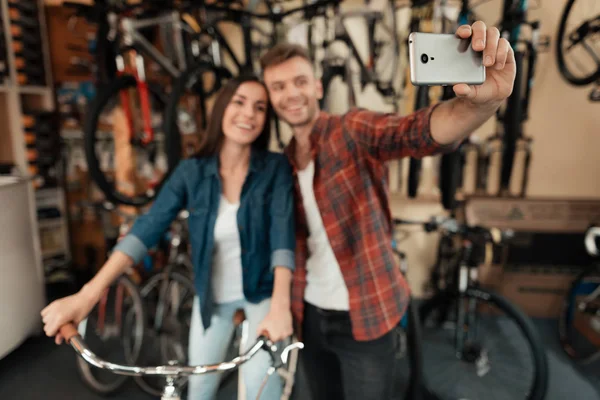 Ein junger Mann und ein Mädchen machen ein Selfie in einem Fahrradgeschäft. — Stockfoto