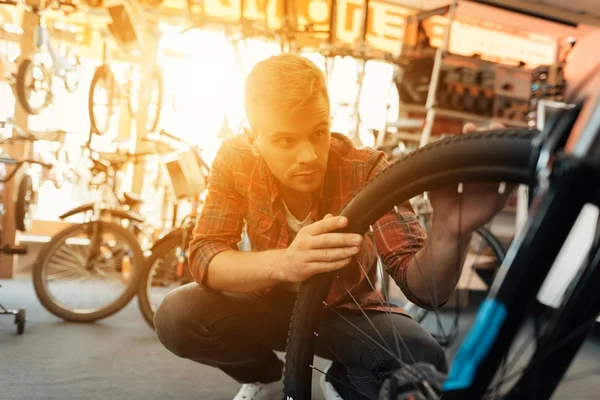 Ein junger Mann begutachtet ein Rad vom Fahrrad. — Stockfoto