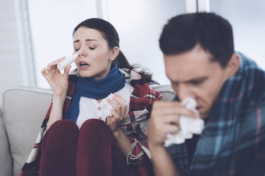 Çift battaniyelere sarılmış kanepede oturuyor. Erkek ve kadın hasta. Onlar kötü bir soğuk var